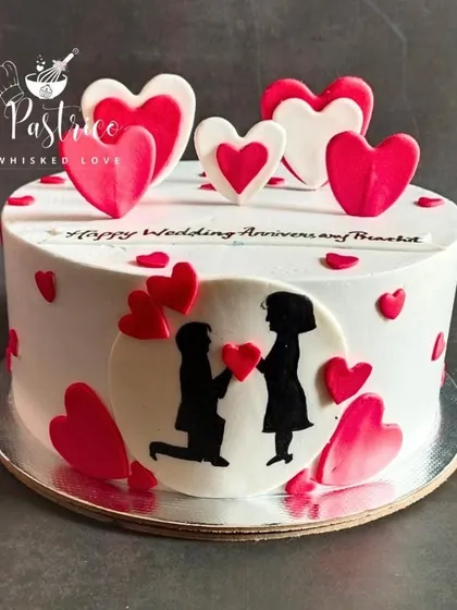 This anniversary cake tells a love story with a simple, beautiful silhouette of a proposal. Surrounded by red and white hearts, it’s a sweet and personal way to celebrate a special day.