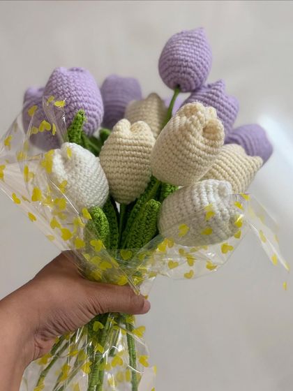 A full bouquet of handmade crochet tulips in soft lavender and cream. This arrangement is wrapped in cellophane with a cute heart pattern, making it a lovely gift.