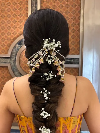A close-up of the fishtail braid adorned with a hair accessory and baby's breath. The combination of jewelry and fresh flowers is one of my favorite ways to style a bridal braid.