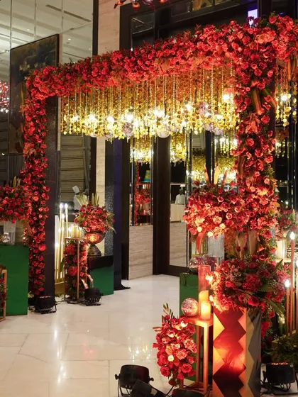 A close-up of this opulent entrance, where a dense arch of red roses is paired with a ceiling of hanging golden crystals and disco balls, blending tradition with glamour.