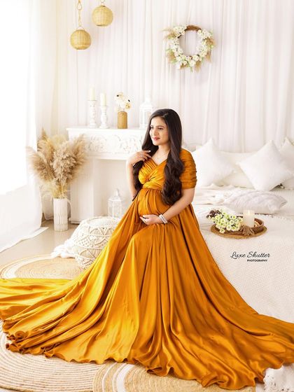 A beautiful portrait of the mom-to-be looking thoughtfully out the window, her golden gown glowing in the soft light.