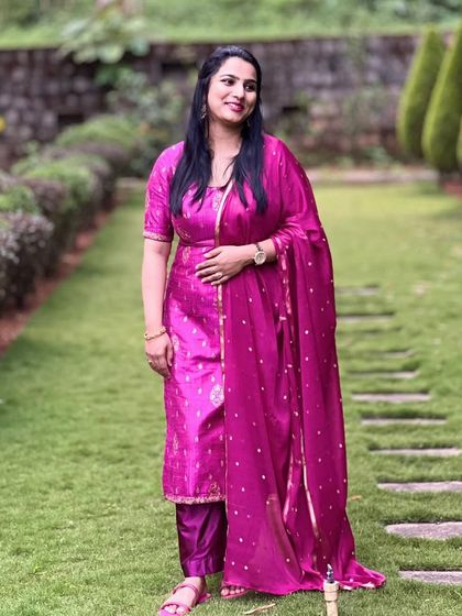 Prathiksha in her pink salwar suit, captured in a beautiful garden setting.