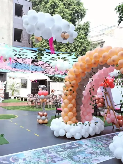 A whimsical fairytale theme with rainbow and cloud balloon decorations in the outdoor area.