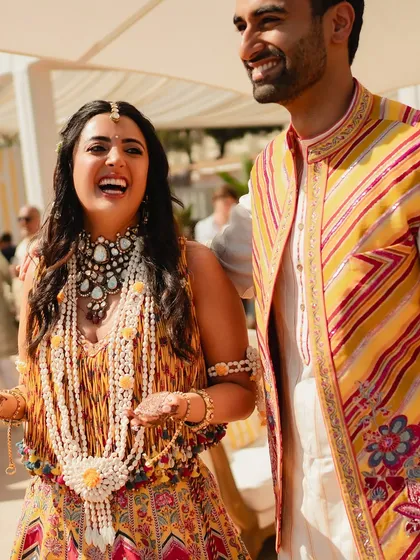 The pure joy and laughter of the bride and groom, surrounded by the sunny yellow decor of their Mehendi celebration.