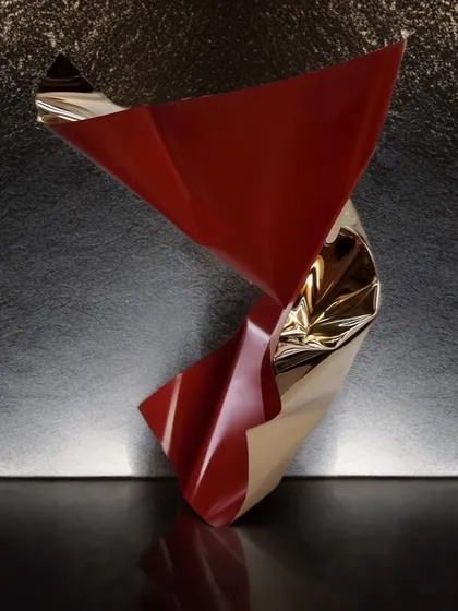 A twisting tabletop sculpture in red and gold from the Meteor collection. Its simple, fluid form makes a bold yet elegant statement on any surface.