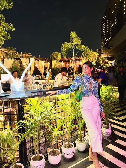A night out at a trendy Delhi bar. I paired a floral bodysuit with high-waisted white pants for a look that's both sophisticated and perfect for a rooftop setting.