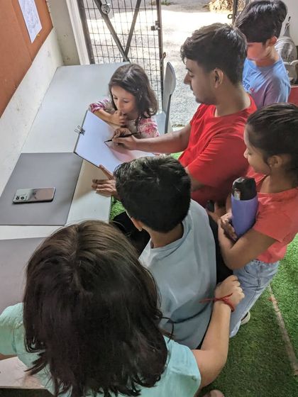 A live demonstration for our younger students. They gather around to watch and learn as our instructor shows them how to draw.