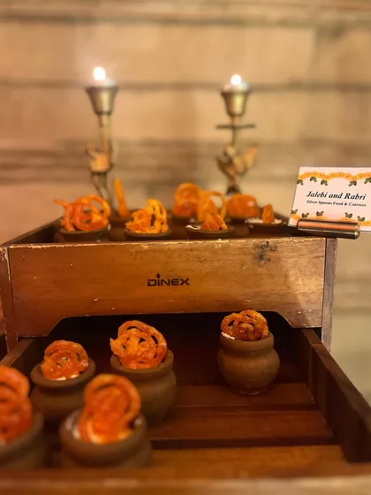 A rustic presentation of Jalebi with Rabri, a classic Indian dessert. The mini jalebis are served in traditional earthen pots, perfect for a winter event or Diwali celebration.