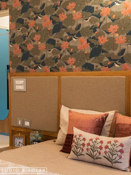 This room uses a bold, floral lotus wallpaper as a feature behind the bed. The warm, earthy tones of the cushions and headboard create a cozy and inviting atmosphere.