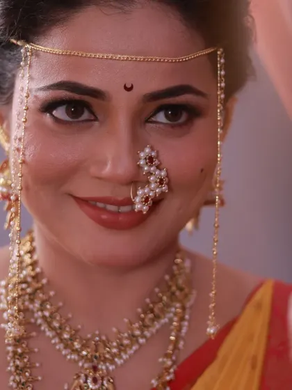 A close-up shot focusing on the bride's expressive eyes, traditional mundavalya, and pearl nath.