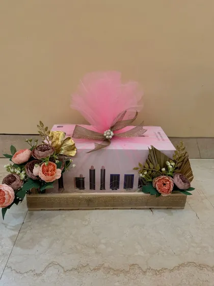 A gift box for the bride, wrapped in pink with a dramatic tulle bow, sitting on a rustic wooden tray with matching floral decor.