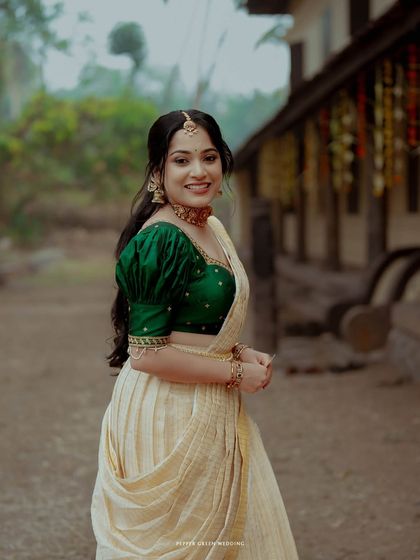 A beautiful portrait of the bride in her traditional Kerala kasavu saree with a vibrant green blouse, her smile radiating happiness.