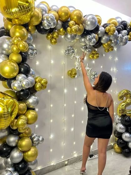 A classic and elegant birthday setup in black, gold, and silver. The balloon arch against a fairy light curtain creates a beautiful and affordable backdrop for any at-home celebration.