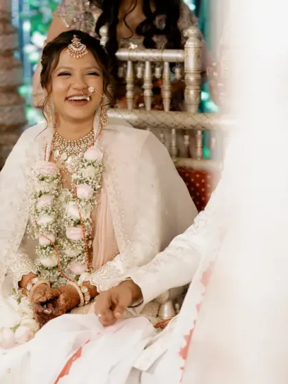 A candid, happy moment of a bride in her white rental lehenga during her wedding ceremony.