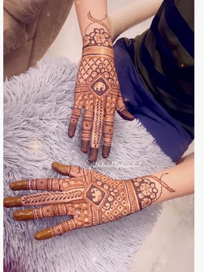 A symmetrical design for Teej, with elephant motifs on both hands. The checkerboard pattern and delicate vines on the arm complete the look.
