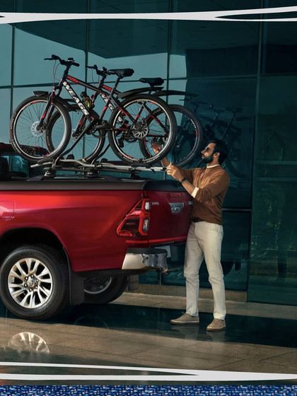 This image for the Toyota Hilux campaign showcases the vehicle's utility. The model is styled in smart-casual attire, demonstrating how the truck fits seamlessly into an active, urban lifestyle.