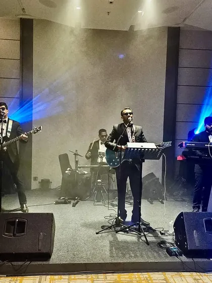 The band on stage, surrounded by professional lighting and smoke effects, at the JW Marriott corporate event.