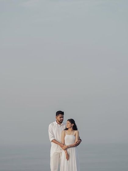 A minimalist pre-wedding portrait using negative space. The simple composition of the couple against the vast, hazy sky creates a powerful and artistic image.