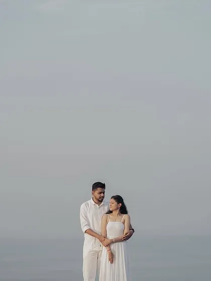 A minimalist pre-wedding portrait using negative space. The simple composition of the couple against the vast, hazy sky creates a powerful and artistic image.