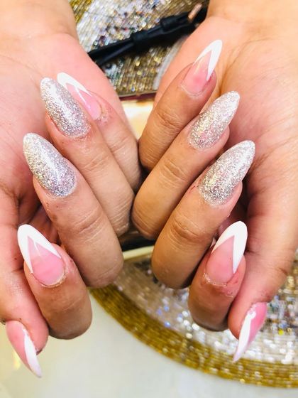 A close-up view of the sharp lines and sparkling glitter in this modern French tip set.