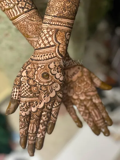 A dynamic pose showing off a detailed bridal design. The focus is on the intricate work on the palms and fingers, with the arm patterns providing a beautiful frame.