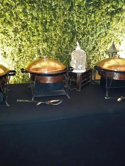 A row of our classic hammered copper chafing dishes set up against a living green wall, perfect for adding a rustic yet elegant touch.