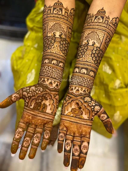 This bridal design features bride and groom figures on the palms, surrounded by peacocks and elephants. The top of the arms is adorned with palace-like architecture, completing the royal look.