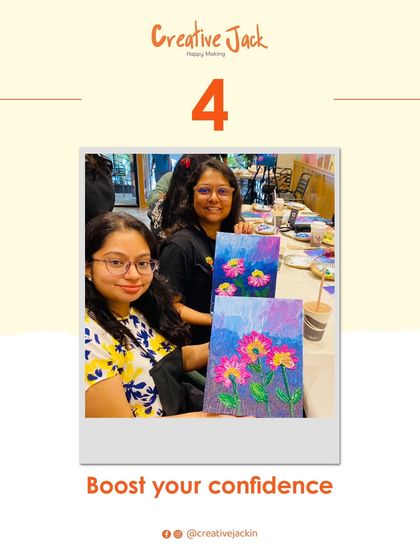 Two friends smile for the camera, holding up their matching floral paintings. Art is a wonderful way to boost confidence and have fun with friends.