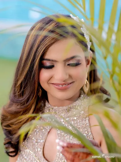 A beautiful close-up portrait of the bride, with natural elements framing her face, showcasing her radiant makeup and happy smile.