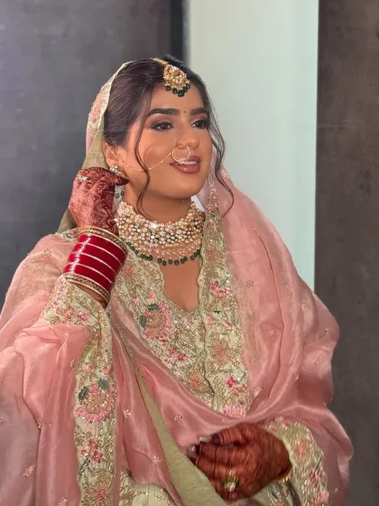 A classic Punjabi bridal look for Nam's Lava ceremony. The pastel pink suit, traditional jewelry including the maang tikka and nose ring, and soft glam makeup create a timeless and elegant style.
