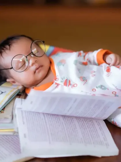 An adorable shot of a newborn sleeping on open books, capturing the quiet and peaceful nature of the first few weeks.