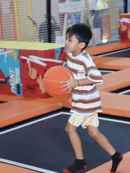 A young boy gets ready to shoot some hoops while bouncing. The combination of jumping and basketball makes for a uniquely fun and active game.