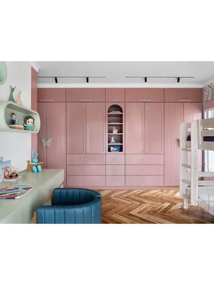 The daughter's bedroom wardrobe, finished in pastel mauve with an arched display niche, provides ample storage while adding to the room's playful charm.