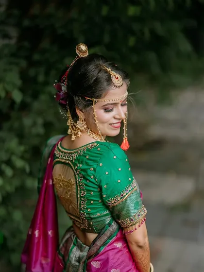 A back-profile shot of a bride, showcasing the intricate design of her blouse and her traditional hairstyle and jewellery.