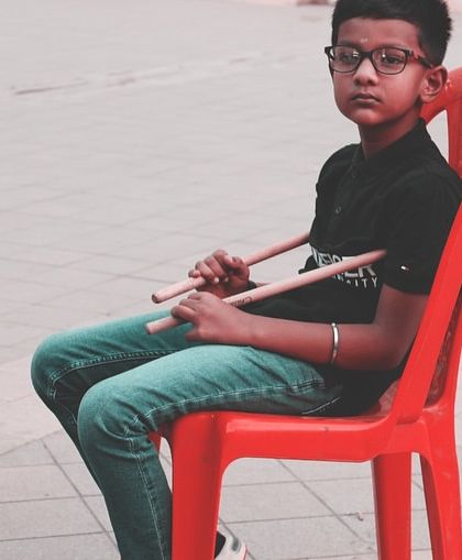A young drummer waits patiently for his turn to perform. The discipline and focus required for live shows are an important part of the learning process.