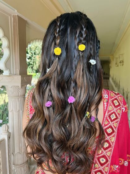 A bohemian-inspired half-up style with multiple small braids and scattered tiny flowers, perfect for a Mehandi.