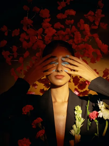 An expressive shot where the model covers her eyes. This gesture, combined with the floral elements, creates a sense of vulnerability and beauty.