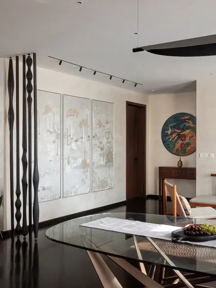 Art is a central theme in the 'Rambagh' residence. Here, the dining area is set against a backdrop of curated art pieces, including a custom black-and-white column and a triptych, demonstrating how we design spaces that serve as a personal gallery for our clients.