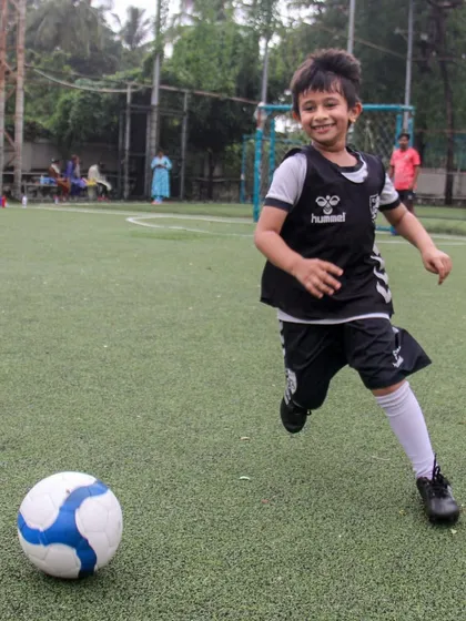 This is the pure joy of football we aim to inspire in every child. A young player breaks away with the ball, a huge smile on his face, embodying the fun and freedom at the heart of our coaching philosophy.