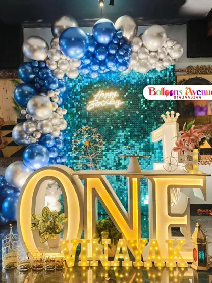A wider view of the blue and silver first birthday party, showing the full balloon arch and the elegant arrangement of props.