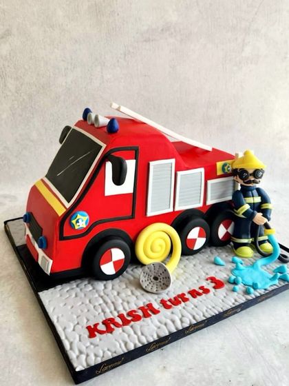 A structural fire engine cake for Krish's 3rd birthday. The entire truck is a cake, complete with a firefighter and a hose putting out a "fire."