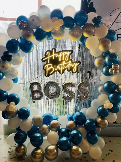 A "Happy Birthday Boss" celebration with a blue, white, and silver balloon ring. The setup includes a shimmer curtain for extra sparkle.