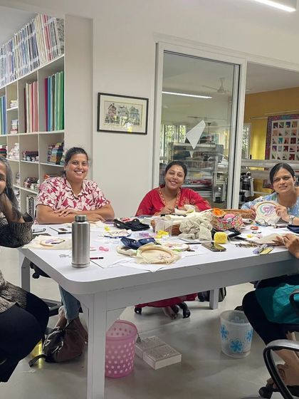 Another view of a workshop in session, with participants seated around a large table, sharing materials and ideas. The sense of community is one of my favorite parts.