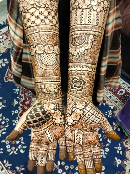 This design features a lot of detailed grid work, or jaali, on the palms, contrasted with floral bands on the arms. It's a classic and intricate bridal look.