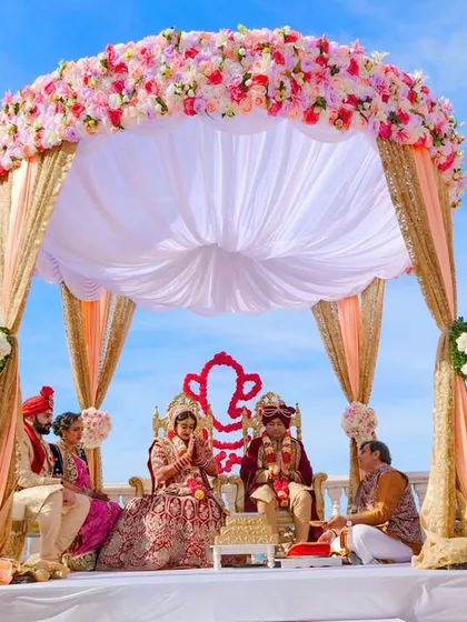 A beautiful daytime wedding ceremony under a stunning floral mandap. We capture the grandeur of your wedding setup and the sacred rituals, ensuring every detail of the ceremony is preserved against a bright, clear sky.