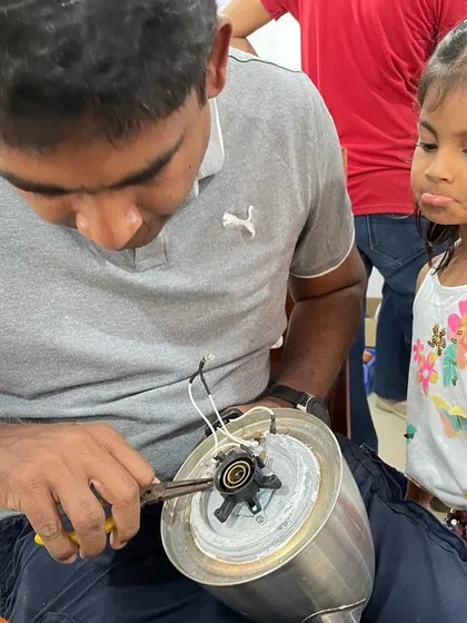 Curiosity knows no age. We love seeing moments like this, where a young girl watches with fascination as a mentor works on a kitchen appliance. Our workshops are safe, welcoming spaces for kids to learn practical skills.