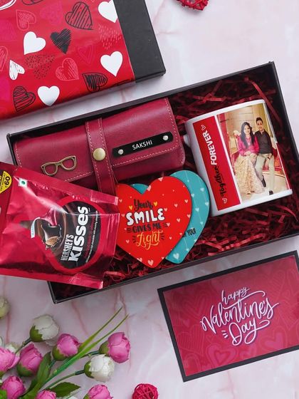 The Valentine Delight Hamper includes a personalized ceramic mug, two heart-shaped tea coasters, a custom eyewear case, and Hershey's Kisses, all presented in a beautiful gift box.