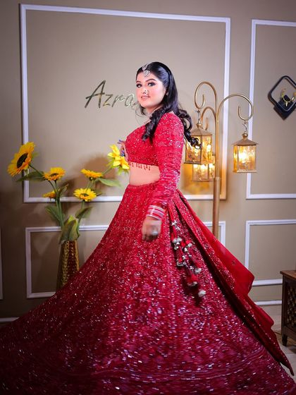 A full-length portrait of a bride in a stunning, sequined red lehenga.
