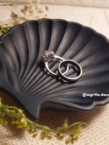 Our bestselling mini shell dish in a solid navy blue, holding a pair of silver rings. It's a simple, elegant, and functional piece.