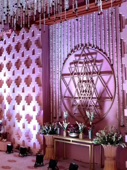 The main stage area of the Shri Yantra wedding, featuring geometric wall panels and hanging floral strings, all centered around the sacred symbol.